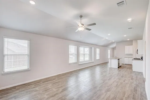 a view of an empty room with a window and wooden floor