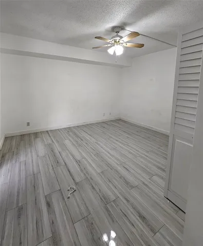 an empty room with wooden floor and chandelier fan