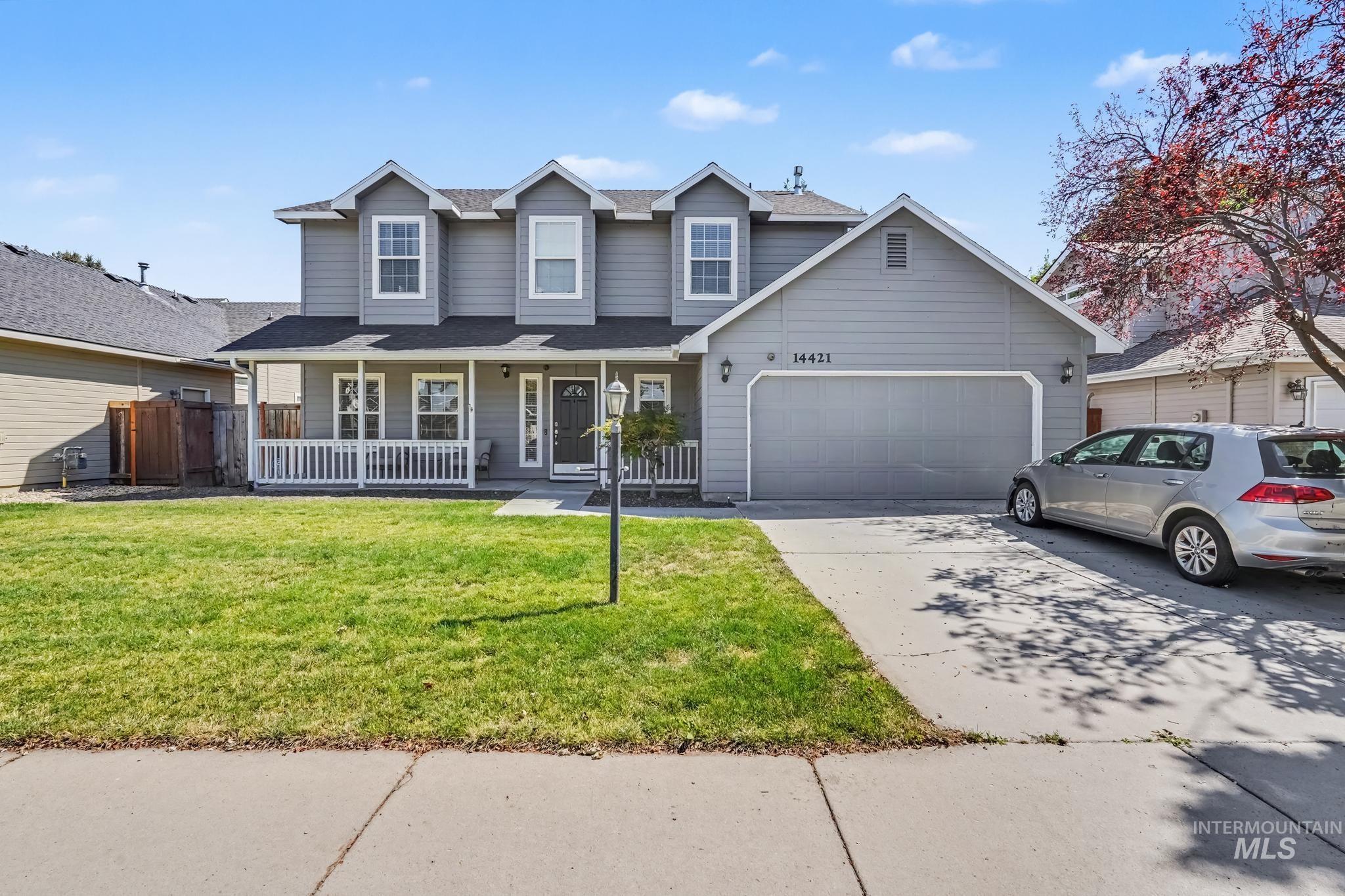 14421 West Stockwell Street Boise, ID 83713 - Photo 1 of 20 Two-story residence featuring light gray siding, a covered front porch with white railing, and a two-car garage