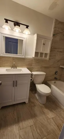 a bathroom with a granite countertop sink mirror vanity and toilet