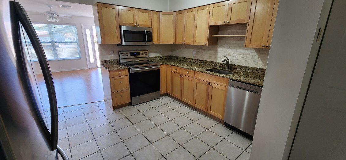 3831 Beacon Hill Road Jupiter, FL 33469 - Photo 4 of 9 a kitchen with stainless steel appliances granite countertop a refrigerator stove and sink