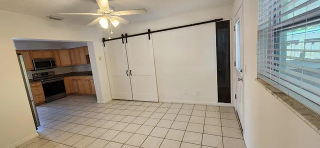 a view of an empty room with kitchen view and a window