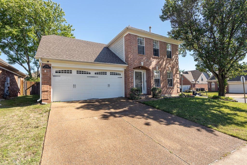 9768 Riggin Drive Memphis, TN 38002 - Photo 30 of 32 Brick facade residence featuring a two-car garage with panel doors, a concrete driveway, and established landscaping