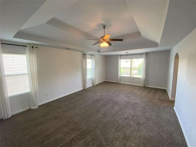 an empty room with windows and chandelier fan