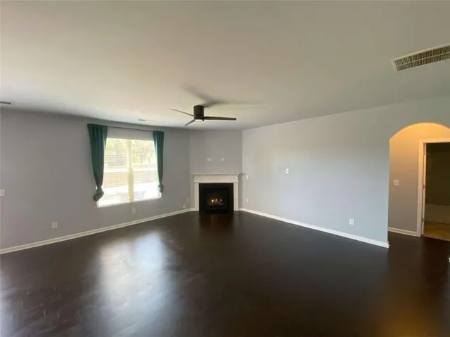 an empty room with wooden floor fireplace and windows
