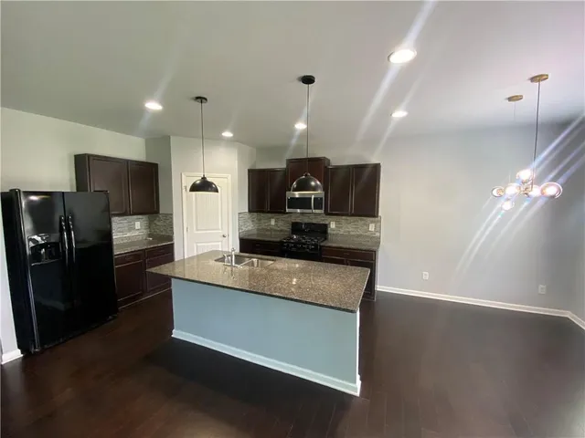 a large kitchen with stainless steel appliances kitchen island granite countertop a refrigerator a stove a sink and a microwave