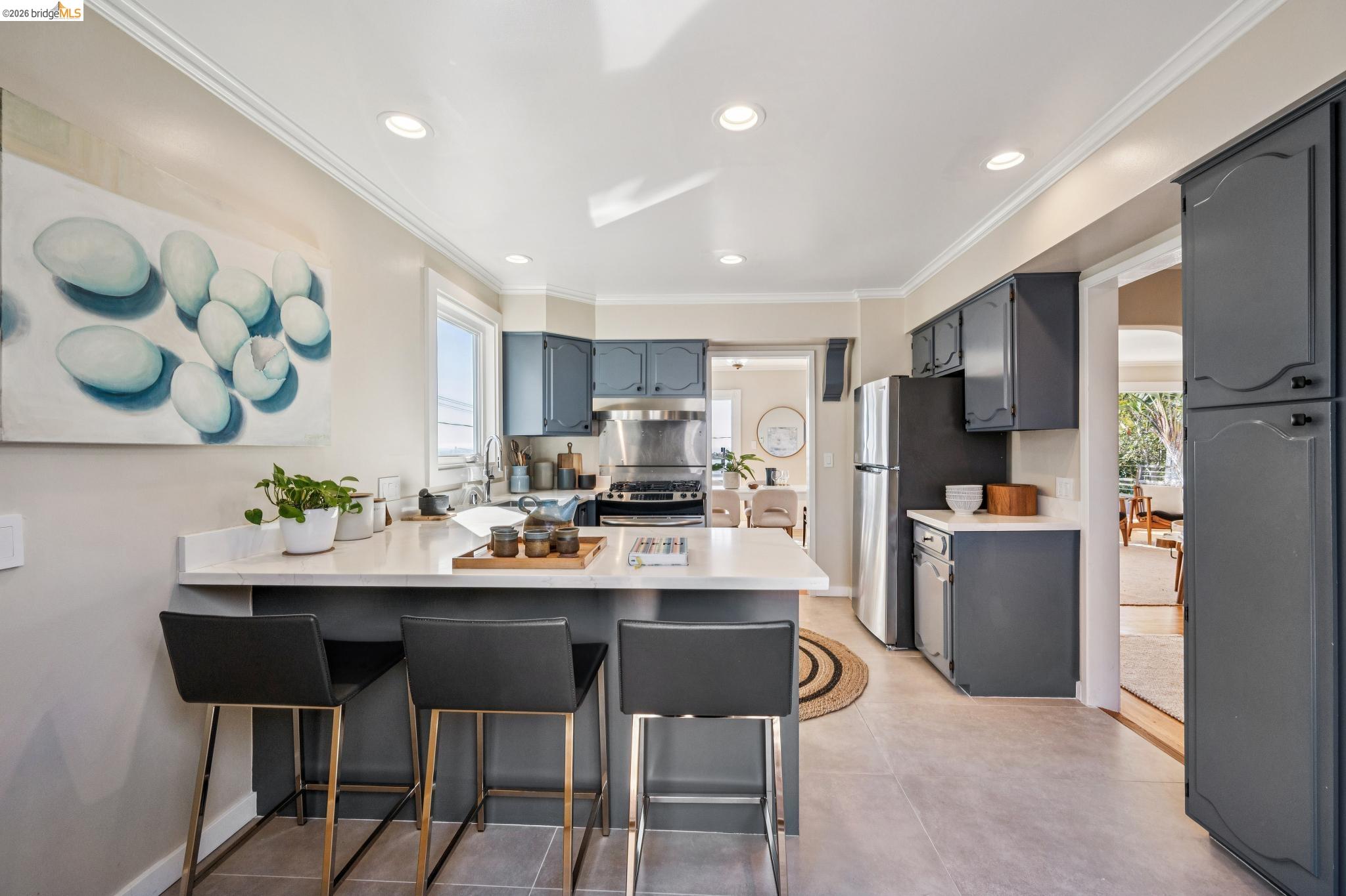 290 Colgate Avenue Kensington, CA 94708 - Photo 26 of 52 Kitchen featuring a kitchen bar, a peninsula, light countertops, crown molding, and stainless steel appliances