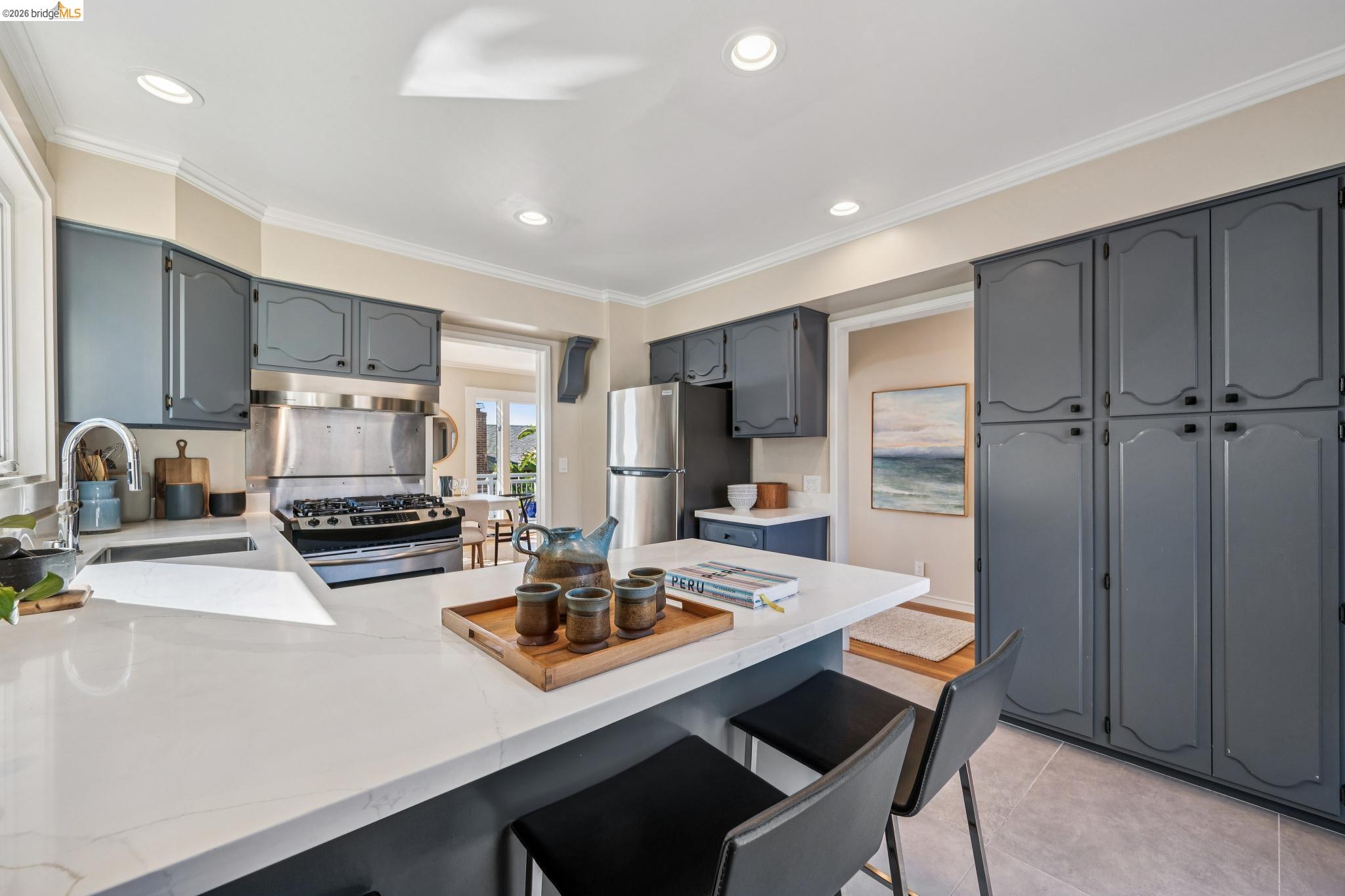 290 Colgate Avenue Kensington, CA 94708 - Photo 30 of 52 Kitchen with a peninsula, a breakfast bar area, stainless steel appliances, light stone countertops, and ornamental molding