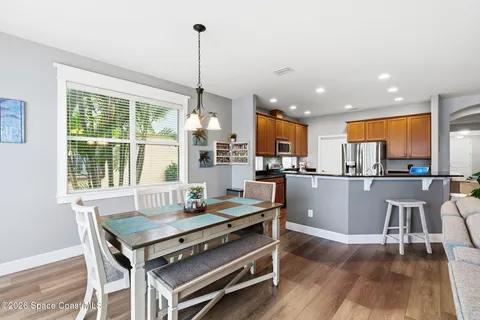a view of a dining room and livingroom with furniture wooden floor a rug a painting and a chandelier