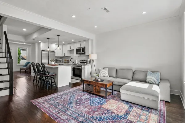 a living room with furniture wooden floor and kitchen view