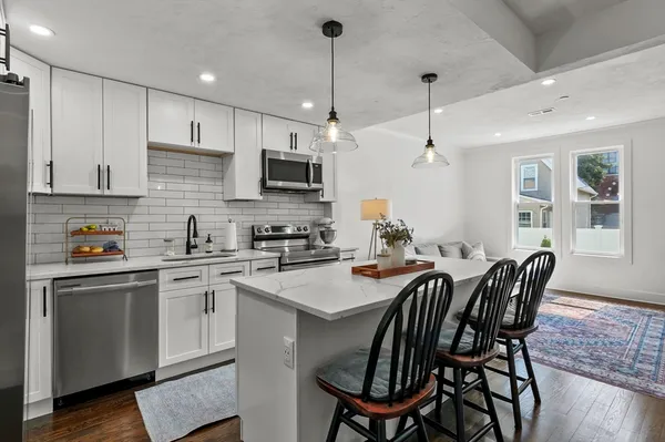 a kitchen with stainless steel appliances granite countertop a sink a stove a kitchen island with a dining table and chairs