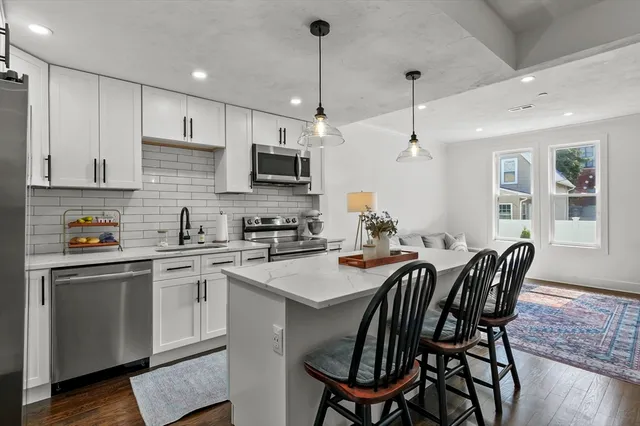 a kitchen with stainless steel appliances granite countertop a sink a stove a kitchen island with a dining table and chairs