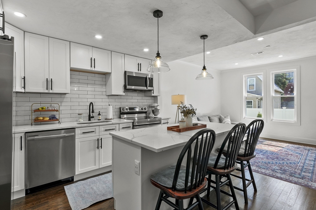 607 Cambridge Street, Unit 4 Worcester, MA 01610 - Photo 9 of 29 a kitchen with stainless steel appliances granite countertop a sink a stove a kitchen island with a dining table and chairs