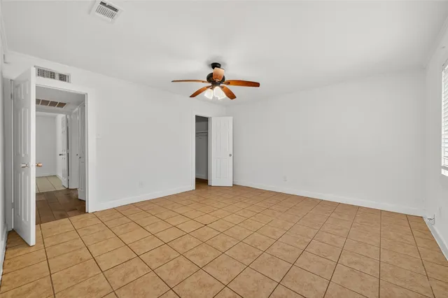 a view of an empty room and chandelier fan