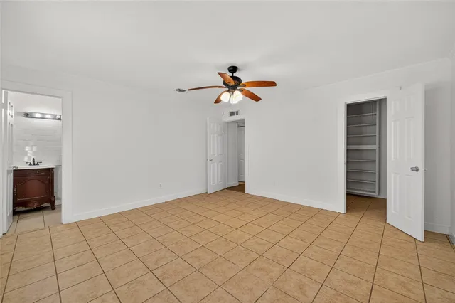 a view of an empty room and chandelier fan