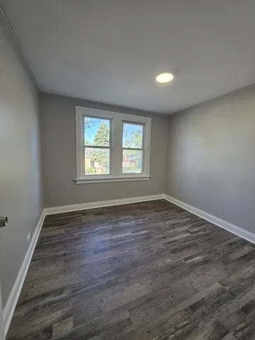 a view of an empty room with wooden floor and window