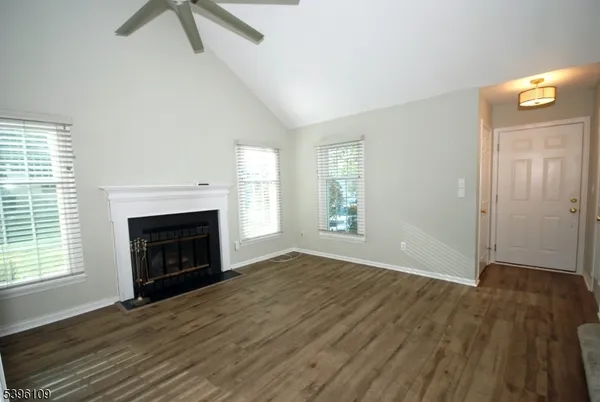 an empty room with windows a fireplace and wooden floor