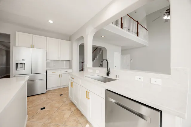 a kitchen with a sink white cabinets and stainless steel appliances