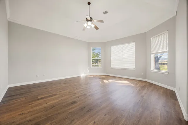 a view of an empty room with window and wooden floor