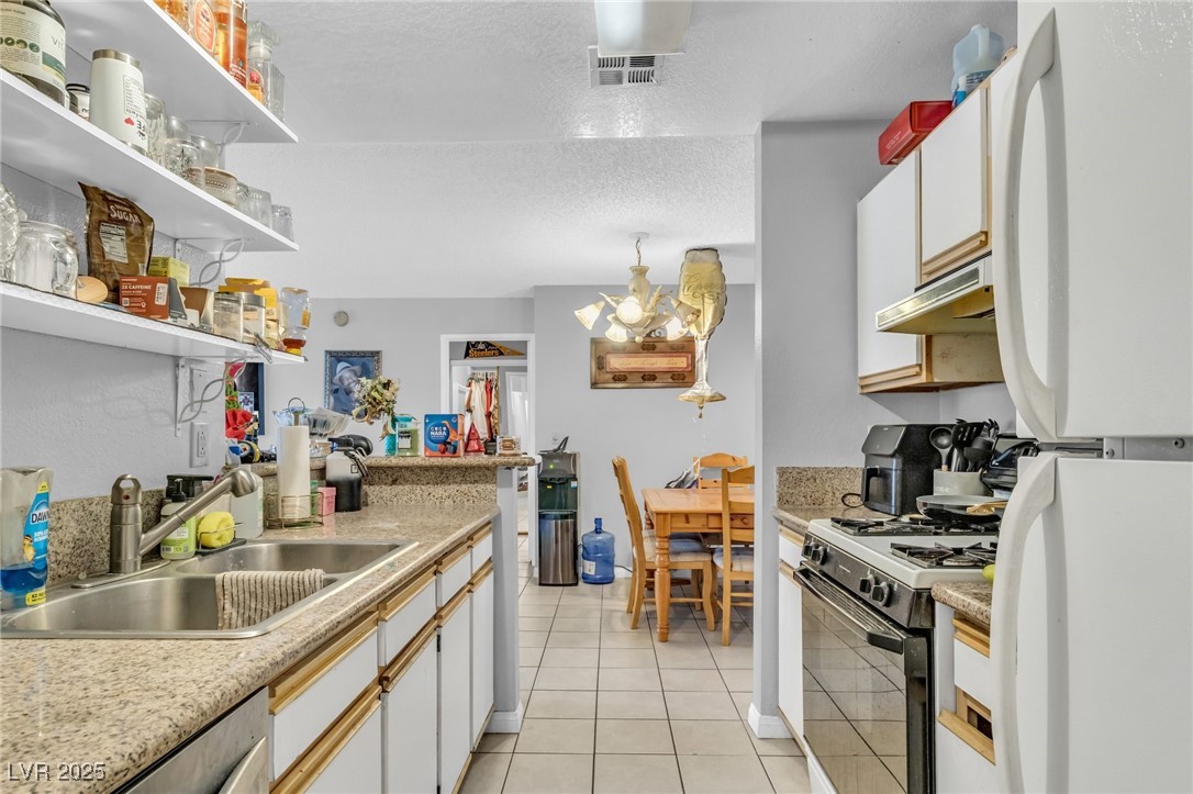 2200 South Fort Apache Road, Unit 1007 Las Vegas, NV 89117 - Photo 13 of 30 Kitchen featuring a sink, white cabinetry, light countertops, open shelves, and range with gas cooktop