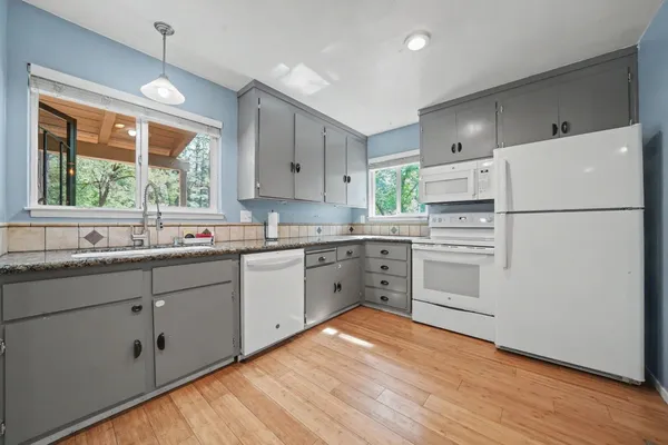 a kitchen with stainless steel appliances granite countertop a sink and cabinets with wooden floor