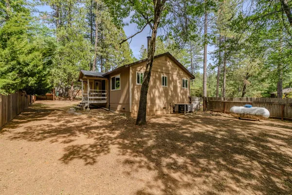 a backyard of a house with large trees and a bench