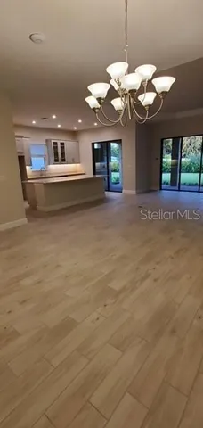 a view of a room with a chandelier fan and wooden floor