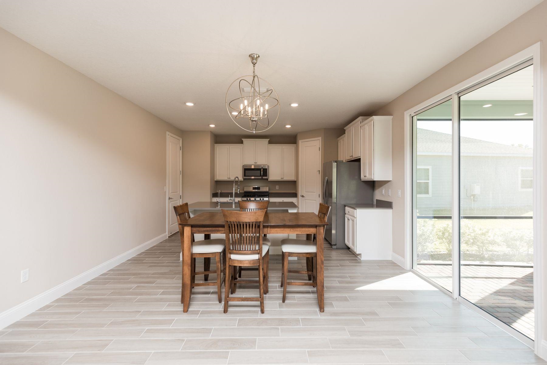 91 Ridgewind Drive St. Augustine, FL 32092 - Photo 12 of 49 a kitchen with stainless steel appliances kitchen island granite countertop a dining table chairs and a refrigerator