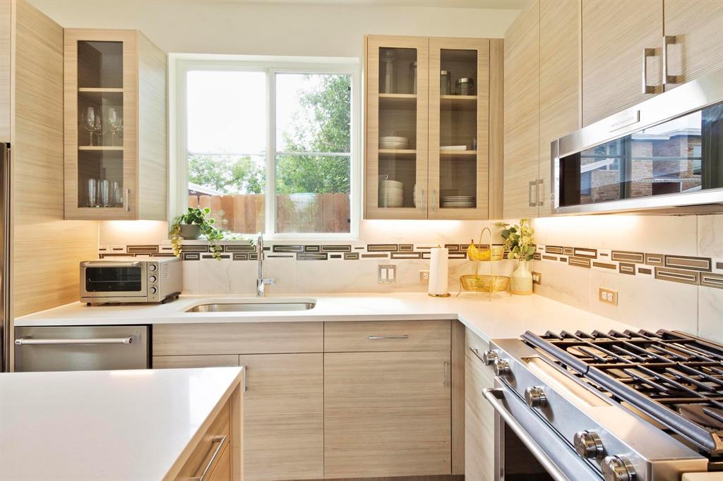 911 Stobaugh Street, Unit 2 Austin, TX 78757 - Photo 4 of 26 Contemporary kitchen featuring wood-finish cabinetry, light-toned countertops, and a decorative tile backsplash