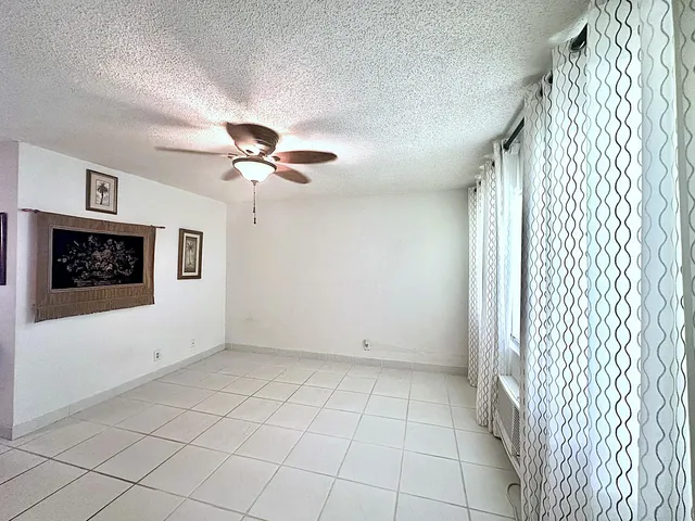 a view of an empty room with a chandelier fan and a fireplace