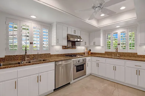 a kitchen with granite countertop a sink appliances cabinets and a large window