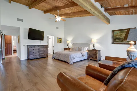 a spacious bedroom with a bed a couch and a flat screen tv
