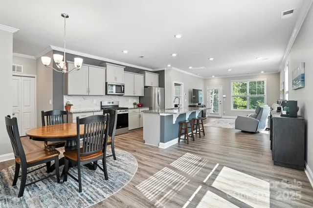 a dining room with wooden floor a chandelier a wooden table and chairs