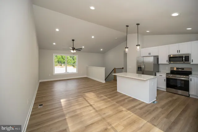 a large kitchen with granite countertop a large counter top a sink stainless steel appliances and cabinets