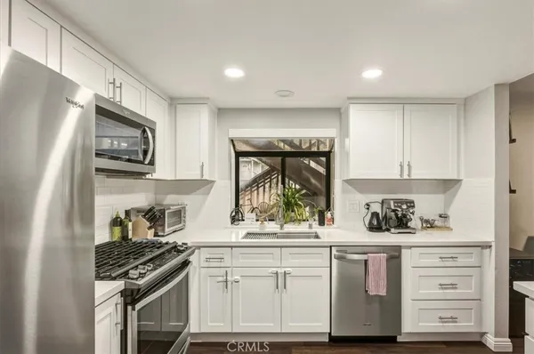 a kitchen with white cabinets and appliances