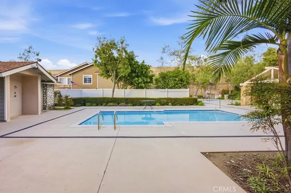 a view of house with backyard outdoor seating and trees in the background