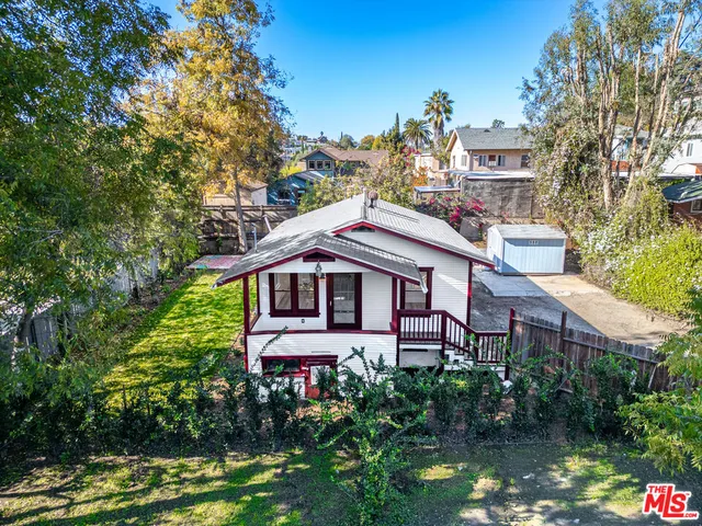 a view of a house with a small yard plants and large trees