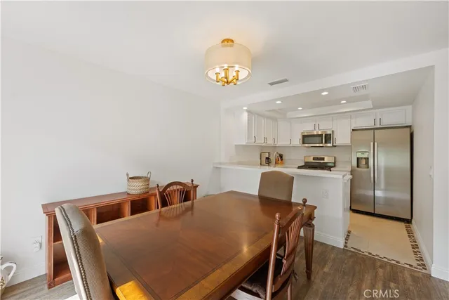 a kitchen with stainless steel appliances granite countertop a dining table chairs and a refrigerator