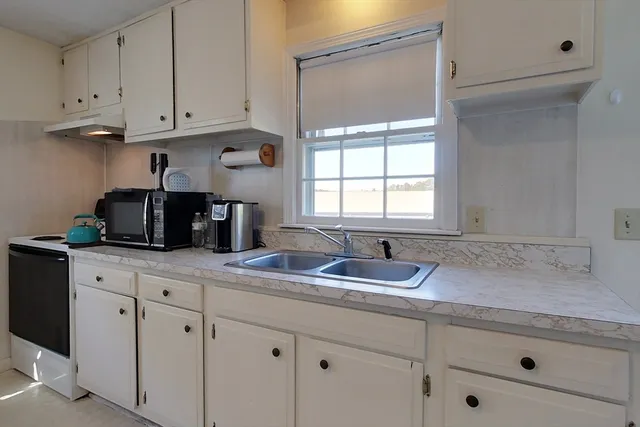 a kitchen with granite countertop a sink and white cabinets