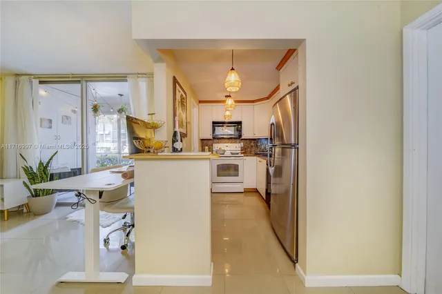 a kitchen with a refrigerator and a view of living room