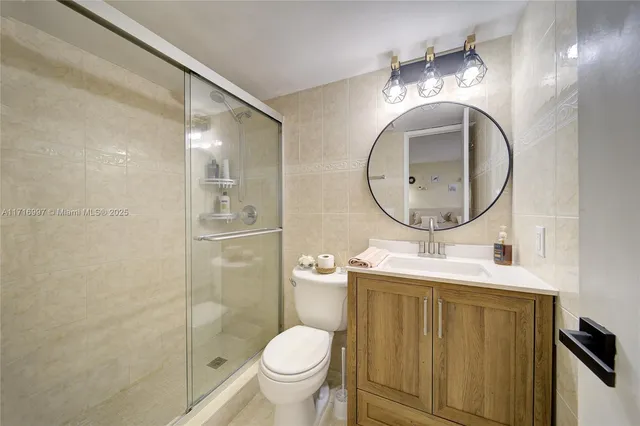 a bathroom with a toilet sink vanity granite and a mirror