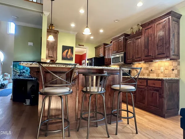 a kitchen with stainless steel appliances granite countertop table chairs and wooden floor