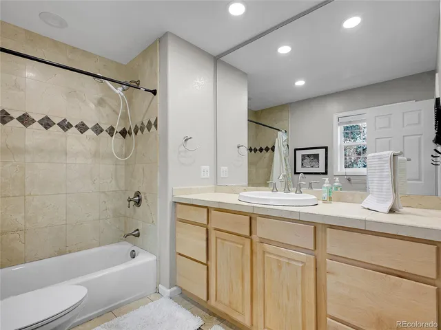 a bathroom with a granite countertop sink a toilet and bathtub