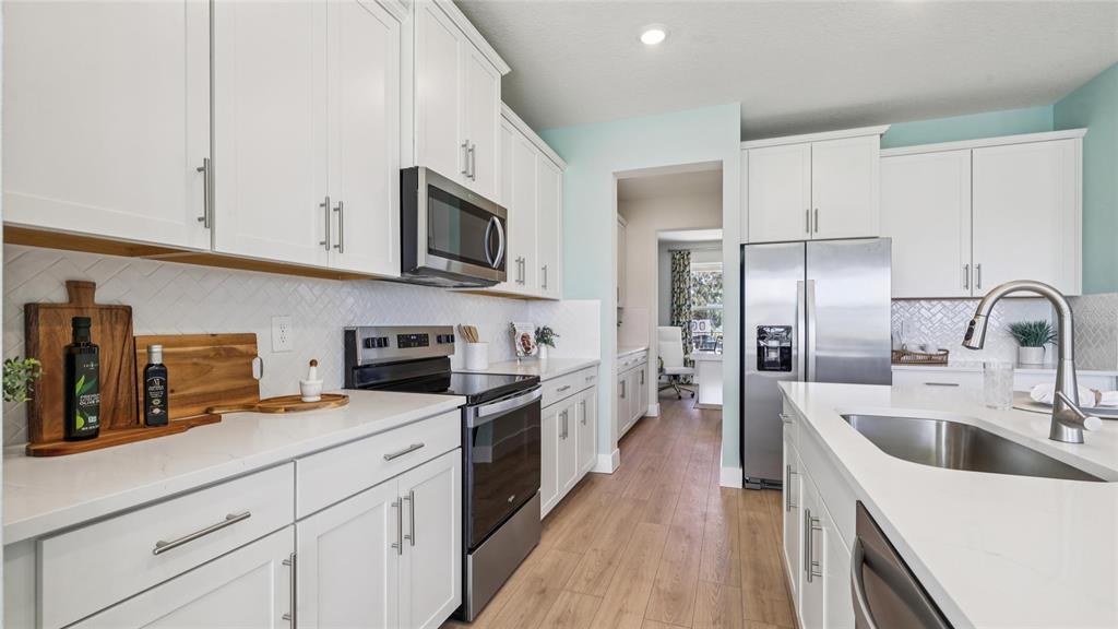 4216 Southwest 52nd Lane Road Ocala, FL 34474 - Photo 7 of 48 a kitchen with stainless steel appliances a sink a stove top oven a refrigerator a counter space and cabinets