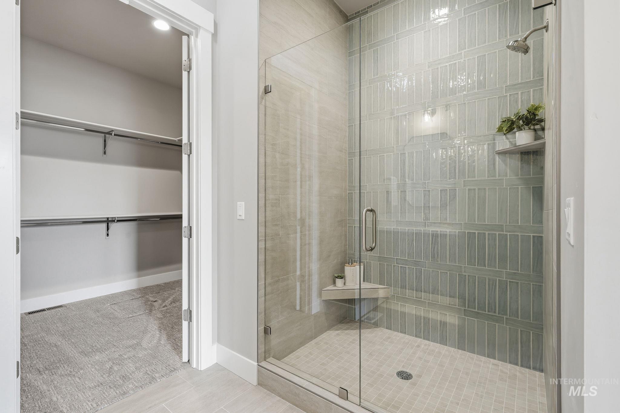 470 South Radiator Way Boise, ID 83716 - Photo 46 of 50 Walk-in shower featuring a glass enclosure, light green subway tile, integrated shelving, and a rain showerhead