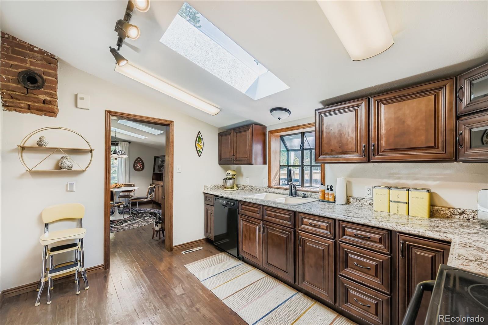 845 Martin Street Longmont, CO 80501 - Photo 6 of 18 a kitchen with stainless steel appliances granite countertop a sink dishwasher stove and wooden cabinets with wooden floor