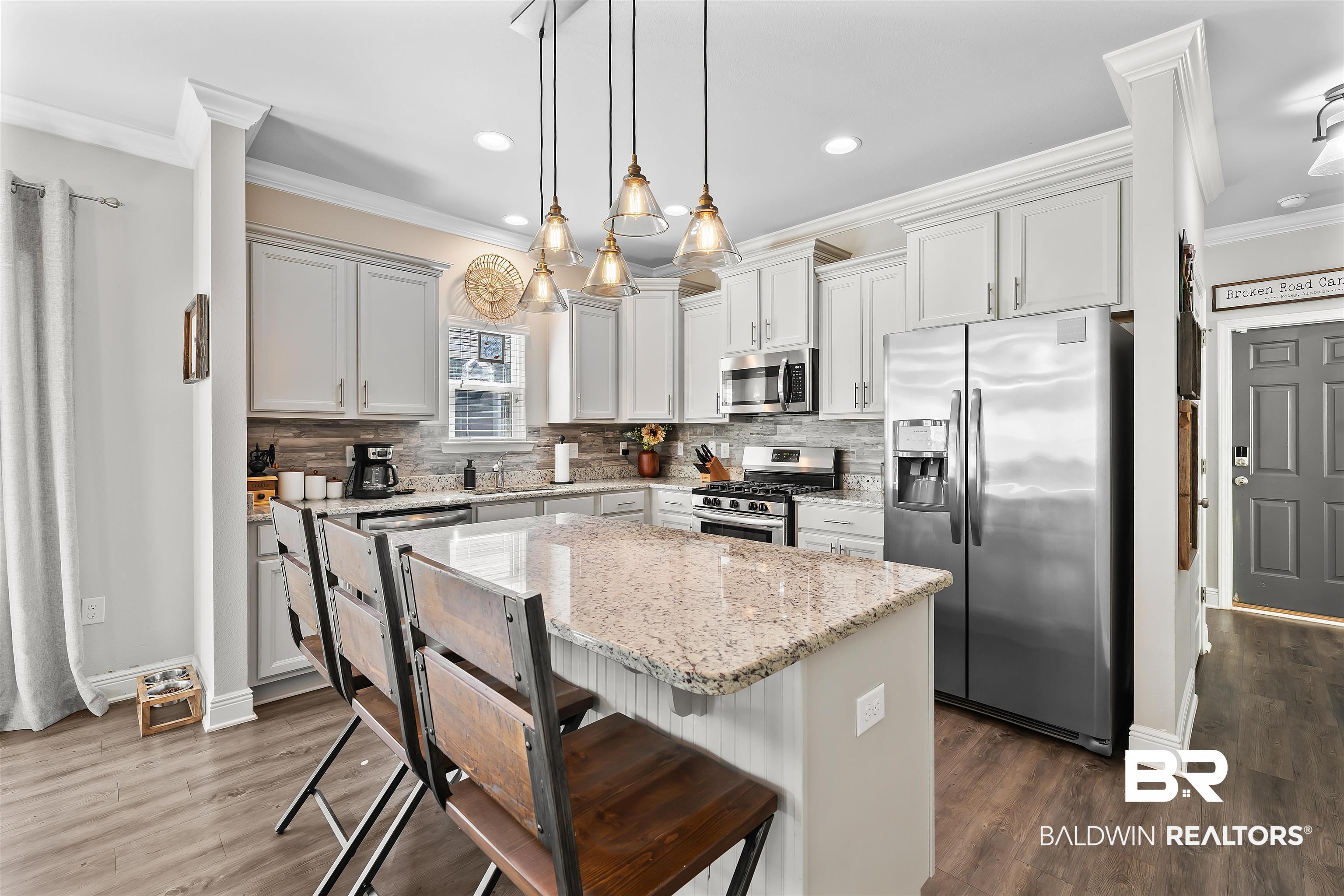 1221 Primrose Lane Foley, AL 36535 - Photo 23 of 29 Kitchen featuring decorative backsplash, appliances with stainless steel finishes, a kitchen island, and ornamental molding