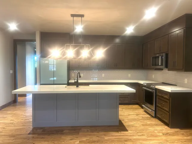 a view of a kitchen with kitchen island a sink a counter top space and stainless steel appliances