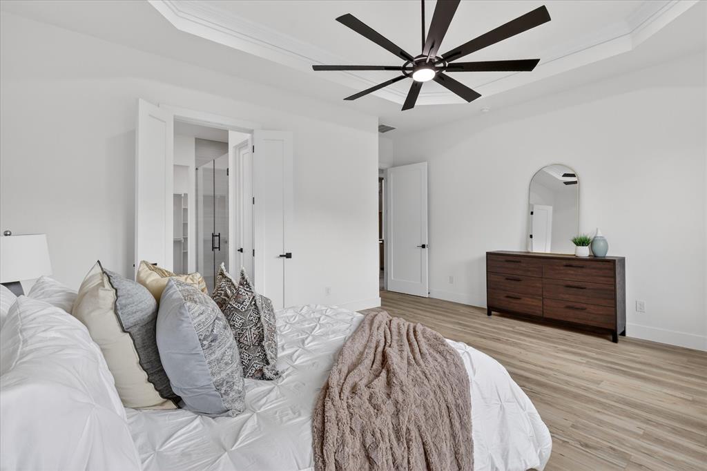 182 Briar Patch Azle, TX 76020 - Photo 18 of 36 Bedroom featuring a raised ceiling, arched walkways, ceiling fan, light wood finished floors, and ensuite bath