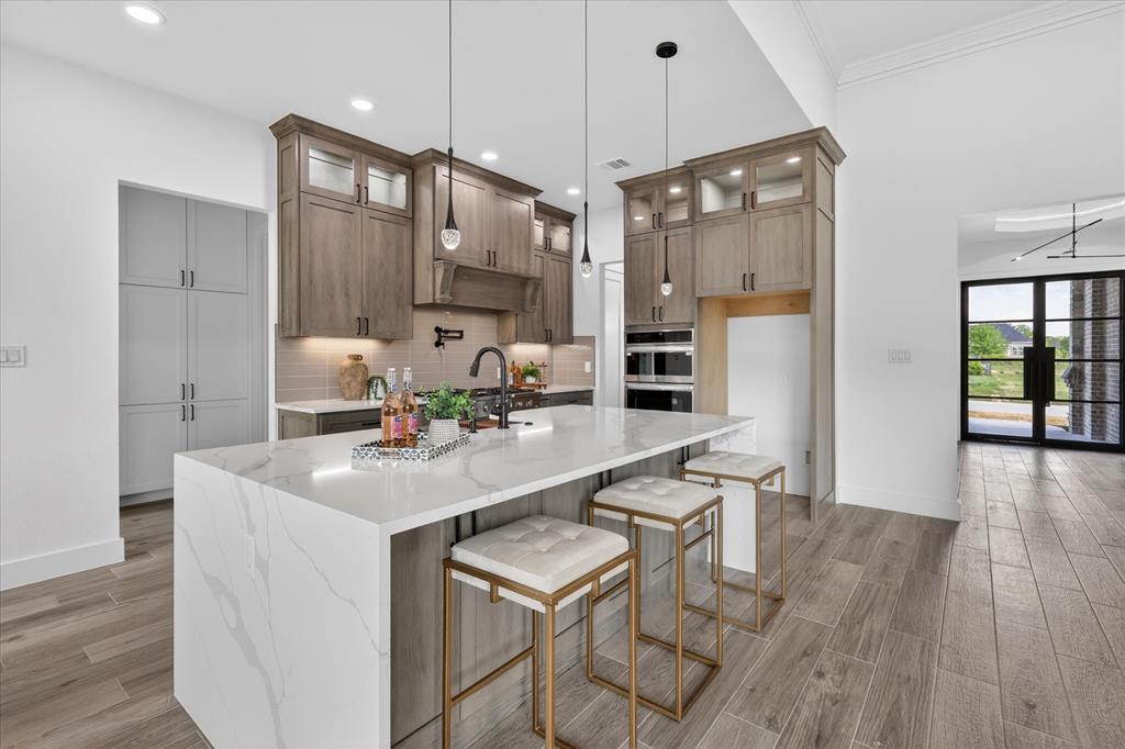 182 Briar Patch Azle, TX 76020 - Photo 6 of 36 Kitchen with light stone counters, light wood-type flooring, a breakfast bar area, an island with sink, and glass fronted cabinets
